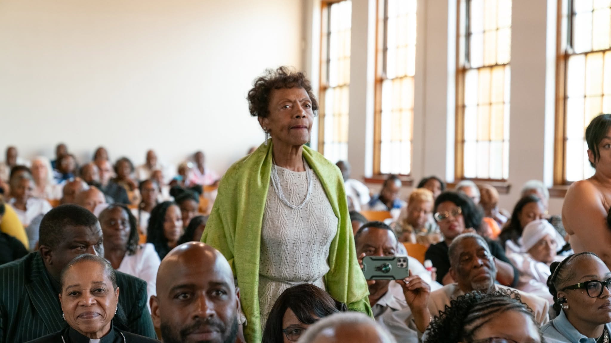 A woman of faith rises — the congregation bears witness