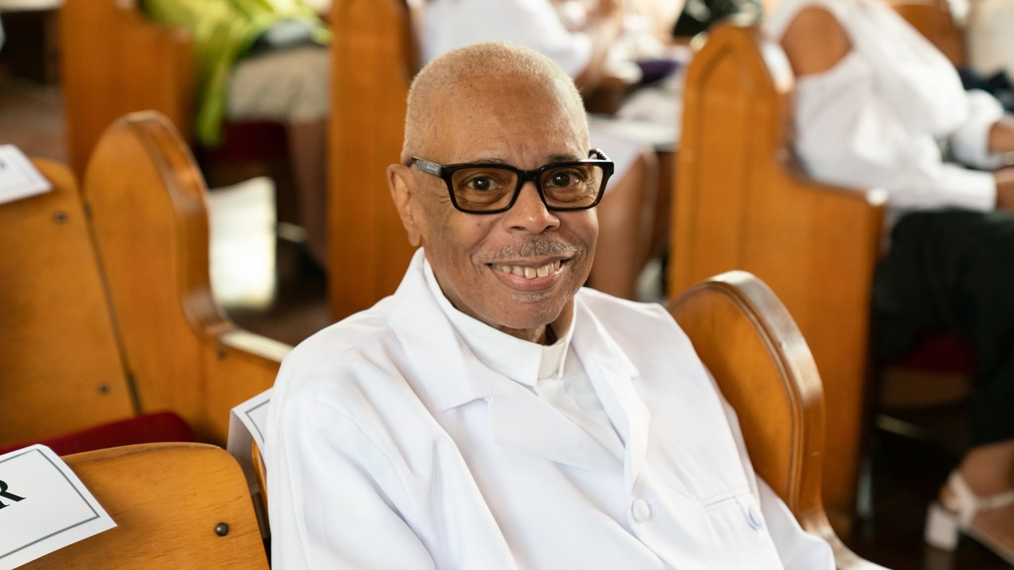 A joyful servant — seated in the pew, dressed in white