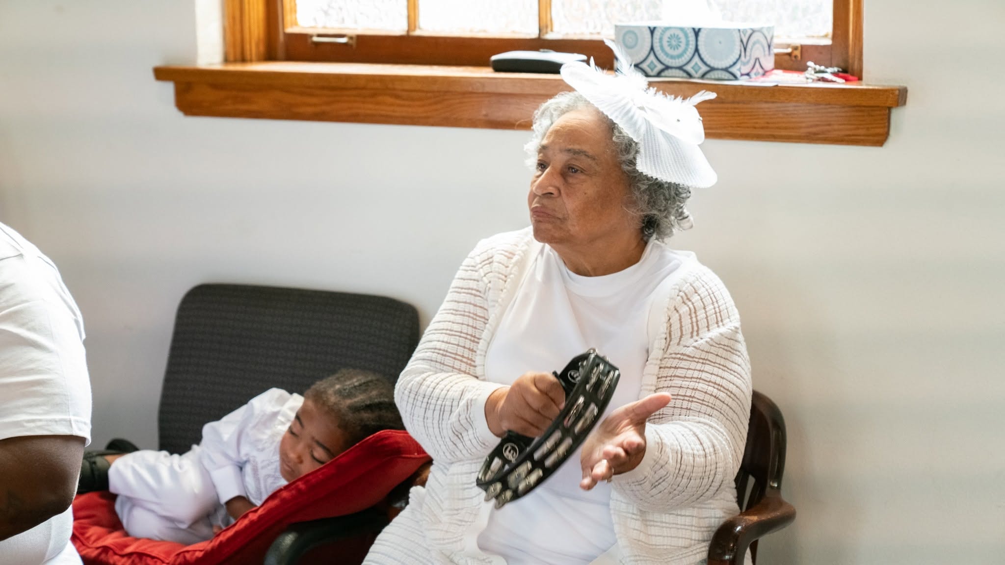 Praise in motion — grandmother plays the tambourine, baby rests